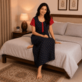 Woman wearing a coffee brown nighty with red contrast sleeves, red front placket, geometric print, soft breathable fabric, and full-length comfortable home wear for women.